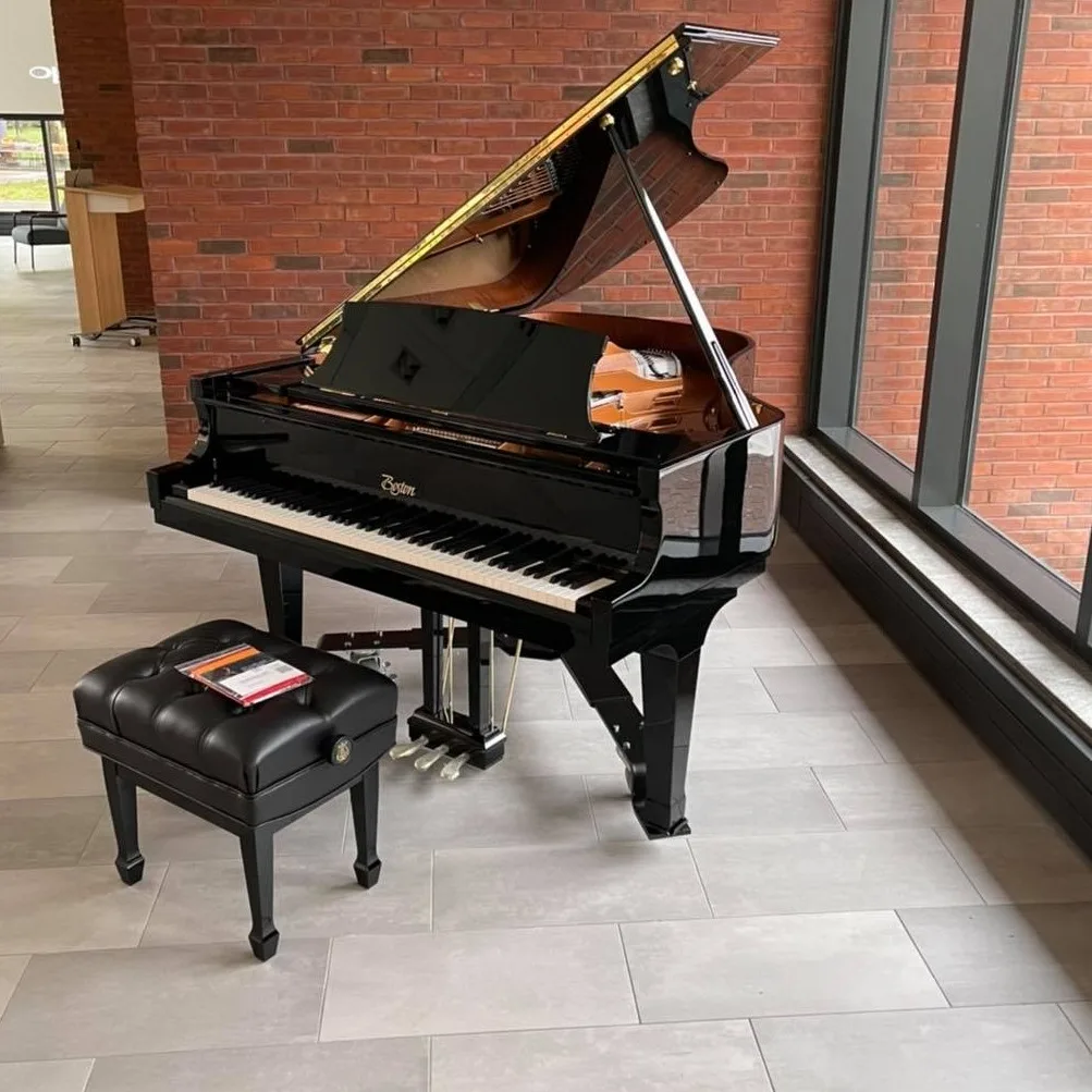 Black grand piano with bench in a showroom