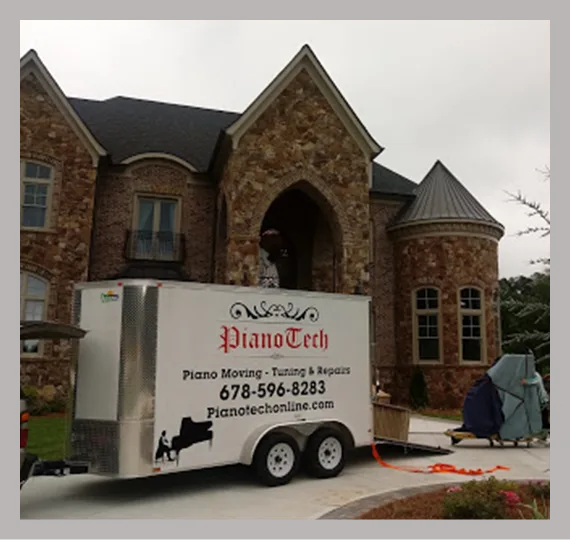 Piano moving trailer parked outside a stone house
