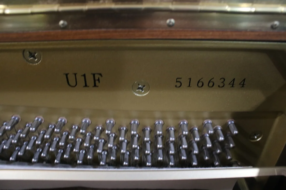 Inside an upright piano, showing its model and serial number plate